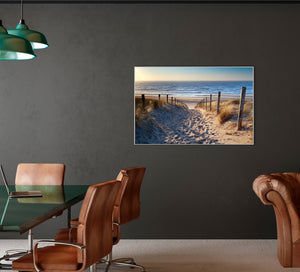 Ein Bild von schönen Nordseedünen, meer und Dünengras hängt an einer dunklen Wand. Das Bild hellt den raum auf.