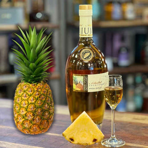 Eine Ananas steht neben der Rum Spirituose von Scheibel auf der Theke. Auf der Flasche steht Pina Gold PREMIUMplus.