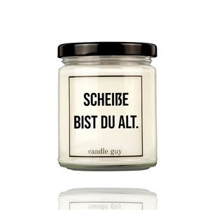 Auf einer Geburtstagskerze im Glas steht der Spruch "Scheiße bist Du alt" Die Duftkerze ist von Candle Guy