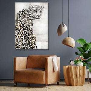 Die Großkatze Schneeleopard schaut von einem mit Arylfarbe gemalten und gerahmten Bild ins Wohnzimmer.