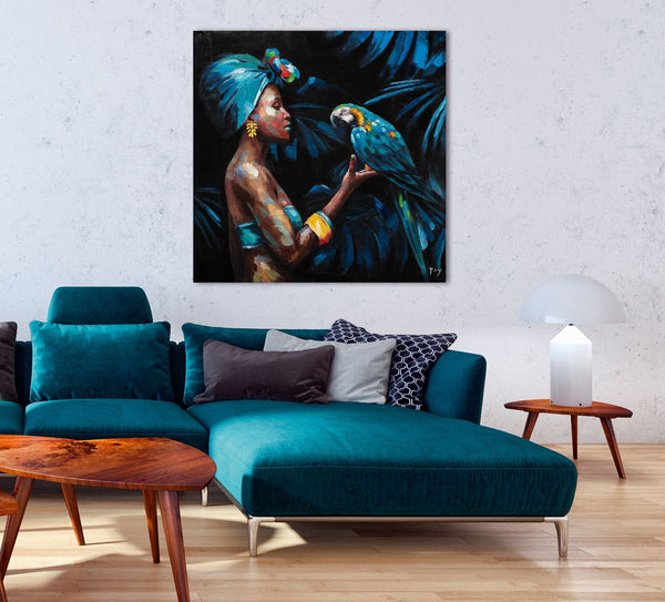 An der Wand hangt eine Gemälde mit einer wunderschönen Frau die auf der Hand einen  blauen Papagei trägt. Das Gemälde passt hervorragend zur Couch die sich darunter befindet.