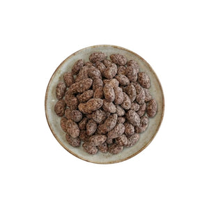 Draufsicht auf einen runden Keramikteller, der mit einer Portion rauer Schoko-Salz-Mandeln von Jalalldor gefüllt ist, freigestellt vor weißem Hintergrund.