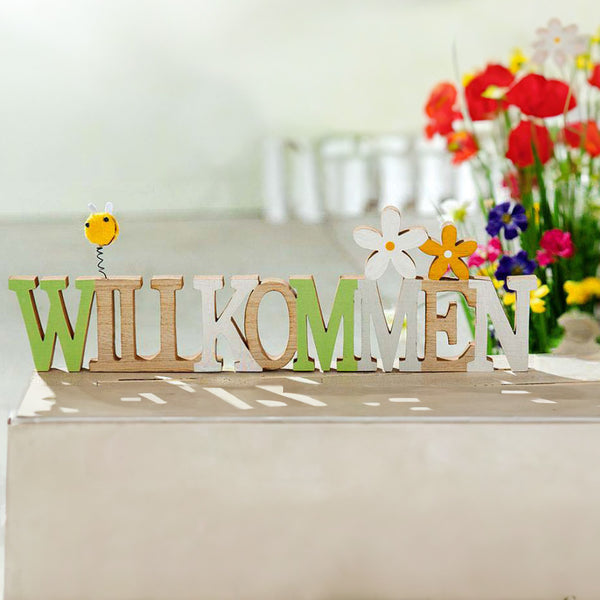 Ein Schriftzug mit dem Wort Willkommen steht dekorativ auf einem Sideboard.