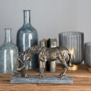 Auf dem Sideboard steht eine Skulptur von einem Reiter der vor seinem Pferd kniet. Ohne Vertrauen geht das nicht.