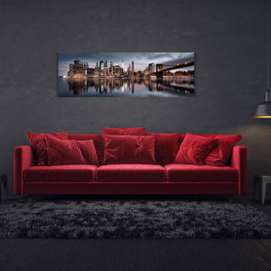 Die Skyline von Manhattan im Abendlicht hängt als Bild über einem roten Sofa.