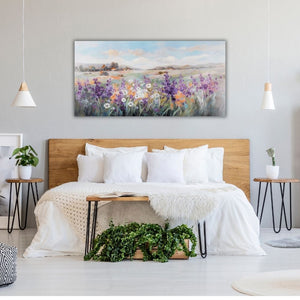 Über einem Doppelbett in einem modernen Schlafzimmer hängt ein großes Gemälde im Querformat. Auf dem Gemälde sieht man Sommerblumen auf einer großen Blumenwiese in der Toskana oder der Provence.