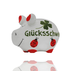 Weißes Sparschwein mit Aufschrift Glücksschwein und bemalten Marienkäfern und 4-blättrigen Kleeblatt