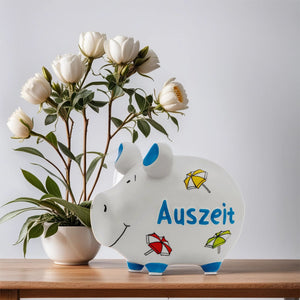 Spardose in weiß mit bunten Sonnenschirmen und der Aufschrift Auszeit