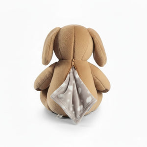 Dreamteam Hund Max hat am Rücken einen Reißverschluss. Hier schaut eine Kuscheldecke für den Wickeltisch heraus. Max das Stofftier ist Kuscheltier und Kuscheldecke in einem.