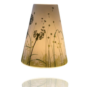 Windlicht aus Keramik mit Pusteblumen und grüner Wiese.