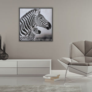 In einem modernen Wohnzimmer hängt an einer sandfarbenen Wand ein schwarz weiß Gemälde. Auf dem Gemälde st ein Zebra mit ihrem Zebrafohlen zu sehen.