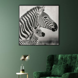Über einem grünen Sessel an einer grünen Wand hängt ein Bild von einer Zebrastute mit ihrem Fohlen. Das Gemälde hat einen schwarzen Rahmen und ist in schwarz weiß.