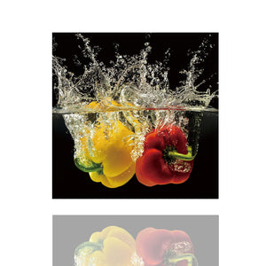 Auf dem Bild sind eine rote und eine gelbe Paprika die in Zeitlupe ins Wasser fallen. Das Bild strahlt Frische und Dynamik aus.