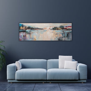 Ein Landschaftsgemälde mit abstraktem Seeblick hängt an einer blauen Wand im Wohnzimmer. Das Acrylgemälde auf Leinwand hängt über einem Sofa.